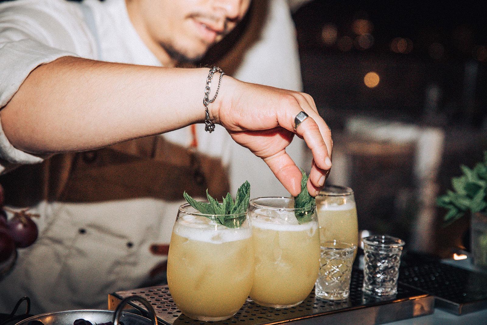 Bartender garnishing cocktails with mint